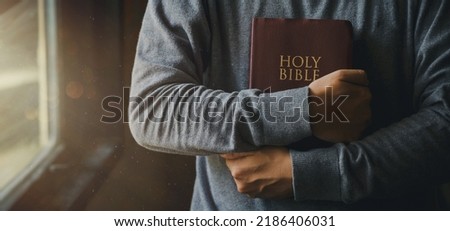 Man is holding and hugging the bible on his chest with atmosphere light from a window representing a symbol of hope and salvation from the Lord. The concept for faith, spirituality, and religion.


 Royalty-Free Stock Photo #2186406031