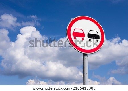 Prohibition road sign No overtaking on blue sky with white clouds background and copy space
