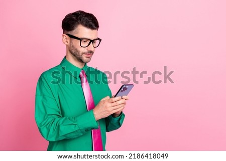 Photo of cheerful positive man dressed green shirt eyewear chatting modern gadget empty space isolated pink color background