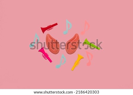 ears around which are colorful trumpets and notes, creative art design, listening to music, pink background