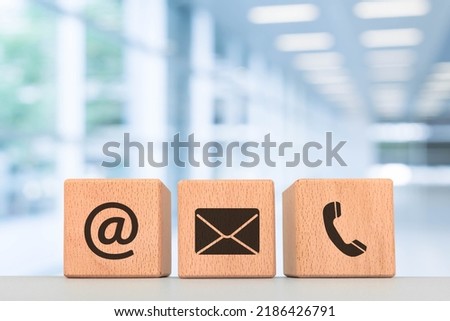 Contact us concept, wooden blocks with email, mail and telephone icons with office background