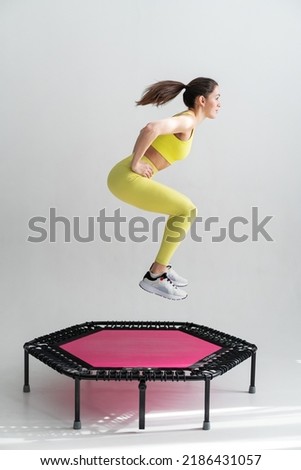 young fitness woman In sportswear jumping on sport trampoline White background Royalty-Free Stock Photo #2186431057