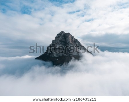 Aerial photograph. Detail of the peak of Beriáin, in the Andía mountain range, rising among the white clouds. In the background a deep blue sky with lots of clouds. Royalty-Free Stock Photo #2186433211