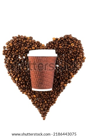 On a white background, a blurred image of a heart made of coffee beans and a disposable cup of coffee. Coffee love concept.