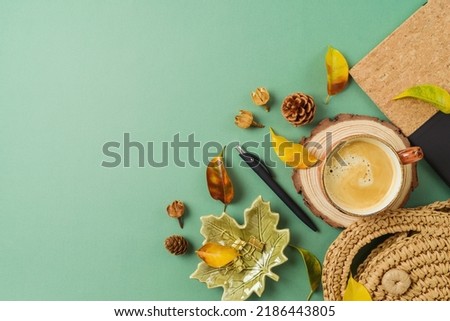 Coffee cup, planner, bag and autumn leaves on green background. Stylish boho table. Back to school concept. Top view, flat lay