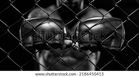 Black and white image of a man in a boxing cage. The concept of sports, Muay Thai, martial arts. Royalty-Free Stock Photo #2186450413