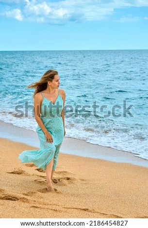 girl in a dress walks by the sea