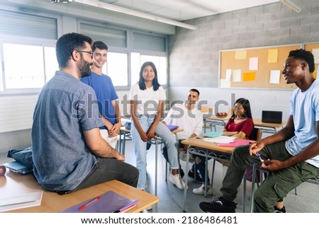 Teenager students listening and talking with friendly young male teacher - Group discussion in High School Education Royalty-Free Stock Photo #2186486481