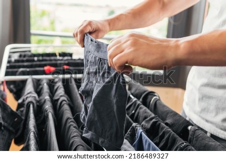 Close up image of a person's hands hanging underwear on a metal indoor clothesline. Householder doing housework happy and content to feel fulfilled. Man completing the laundry. Royalty-Free Stock Photo #2186489327