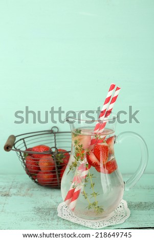Tasty cool beverage with strawberries and thyme, on wooden background
