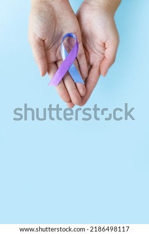 World Autoimmune Arthritis Day. Adult hands holding blue purple ribbon on blue background. RA rheumatoid arthritis illness disease. copy space. vertically photo