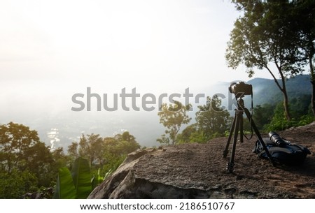 Camera stand on rock of high mountain view with sunlight and foggy in morning time. creative background for using in photo marketplace selling. selective focus.