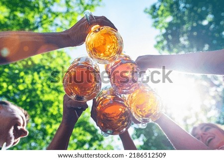 Five friends, men and women, having fun in beer garden clinking glasses with beer in a Beer garden, Munich, Germany Royalty-Free Stock Photo #2186512509