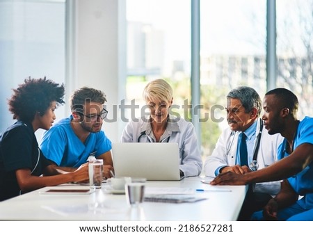 Team of doctors in a meeting planning and brainstorming in a boardroom using a laptop to read notes. Group of healthcare professionals discussing and talking in a modern office Royalty-Free Stock Photo #2186527281
