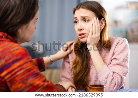 Woman comforting her female friend who sitting at table and feeling depressed. Royalty-Free Stock Photo #2186529095