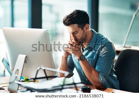 Businessman suffering from a headache or migraine due to stress caused by deadlines and work pressures. Professional in pain feeling anxious, overwhelmed and stressed while busy on his computer desk Royalty-Free Stock Photo #2186538071