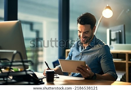 Using his time wisely with smart technology. Shot of a young businessman using a digital tablet during a late night at work. Royalty-Free Stock Photo #2186538121