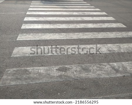 zebra cross signifies safety for pedestrians, this photo was taken in the morning, which has a dramatic effect on the photo, plus the angle when taking the picture adds a very organized perspective.