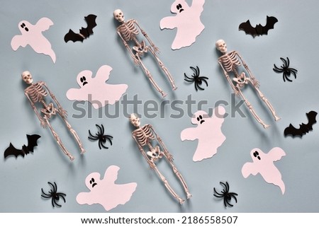 Happy Halloween flat lay composition with ghosts, spiders, skeletons and bats on light blue background. Halloween party greeting card mockup. Banner