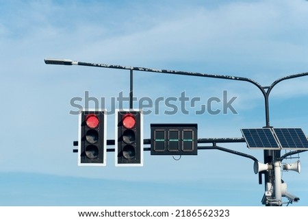 Traffic light red color two way with numeric light board. hanging on a steel arm protruding from the pillar. Install lighting lamps with solar panels. under the blue sky and white clouds at days.