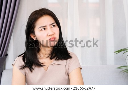 angry Asian woman with unhappy face having mood swings caused by PMS or Premenstrual Syndrome  Royalty-Free Stock Photo #2186562477