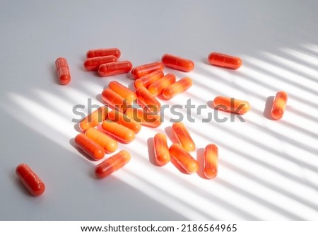 Supplements or vitamins or pills in the orange capsules for health care and treatment under the door shadow.