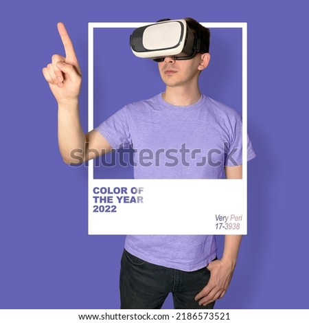 A young slender guy in VR glasses peeking through a frame with a mark of the color of the year 2022. Virtual reality in very peri color. Design in virtual reality