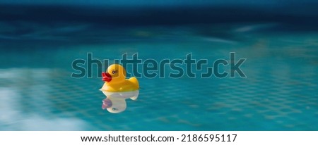 Summer season, the concept of a children's game. A small rubber yellow duck swims in the water in the pool. Toy close-up. A symbol of swimming, childhood, friendship, fun game. Royalty-Free Stock Photo #2186595117