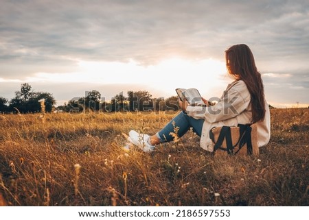 Christian woman holds bible in her hands. Reading the Holy Bible in a field during beautiful sunset. Concept for faith, spirituality and religion. Peace, hope Royalty-Free Stock Photo #2186597553