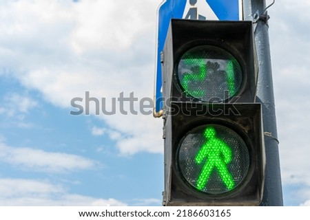 Green light on a pedestrian traffic light against a blue sky. Safe crossing of the road by pedestrians. Place for writing, copy space. Royalty-Free Stock Photo #2186603165