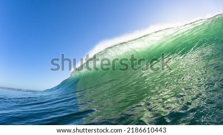 Ocean wave Swimming encounter close-up wall of sea water colors  crashing morning backlit blue sky landscape.