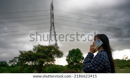 Beautiful asian woman with umbrella talking on the phone while raining and storm coming.Thunderstorm depression, Typhoon, Tornado.Dark cloud storm. Weather forecast outdoor .