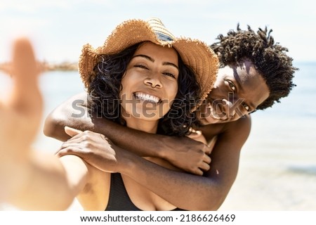 Young interracial tourist couple wearing swimwear make selfie by the camera at the beach.