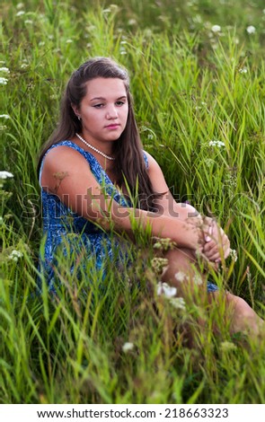 Sad girl sitting in the grass