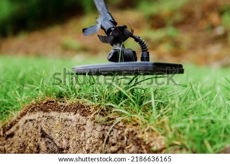 metal detector at work in the forest or field. Search for treasure and ancient values. Archeology. Man with a metal detector. Minesweeper Image. Close-up
