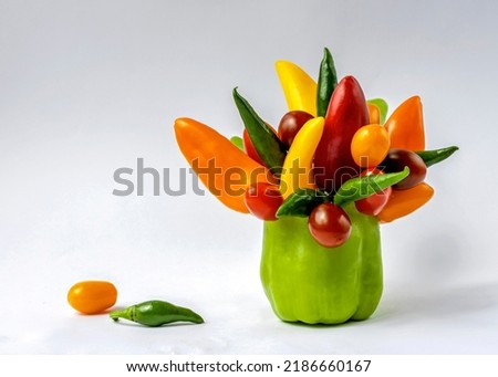 In a glass of sweet peppers, a bouquet of mini peppers and cherry tomatoes close-up isolated on a white background. Composition of vegetables on a white backgroundEdible composition.