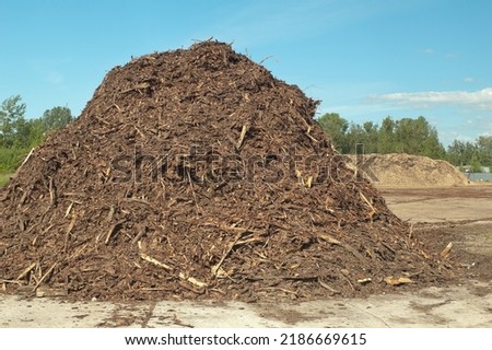 a product of wood processing, in the photo mountains of wood chips and sawdust against a blue sky.