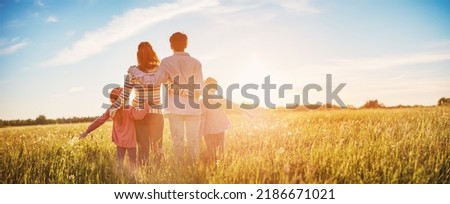 Happy family in the nature together on the evening sunset. Panoramic view. Concept of the vacation and relationship.