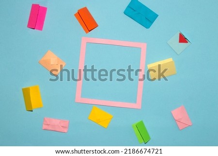 pink frame as copy space on pastel blue background, around frame colorful envelope, letters day