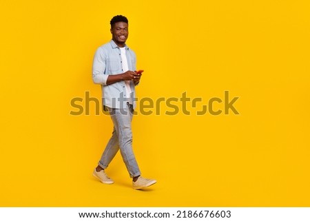 Full size photo of millennial guy walk use smart device communicate blog followers isolated bright color background