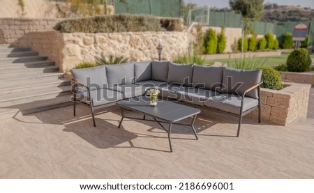 black corner sofa with gray pillows and Metal coffee table in garden interior 