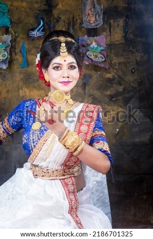 Portrait of beautiful black haired Indian brunette woman face with perfect makeup and wearing jewellery with traditional dress.