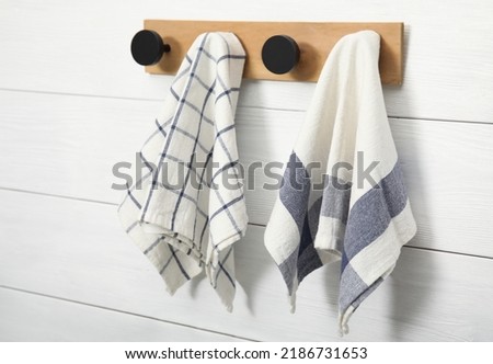 Different clean kitchen towels hanging on rack Royalty-Free Stock Photo #2186731653