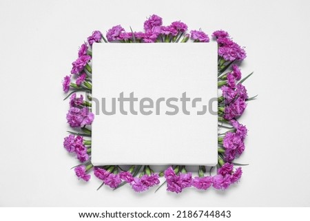 Blank canvas and beautiful violet carnation flowers on white background, top view. Space for design
