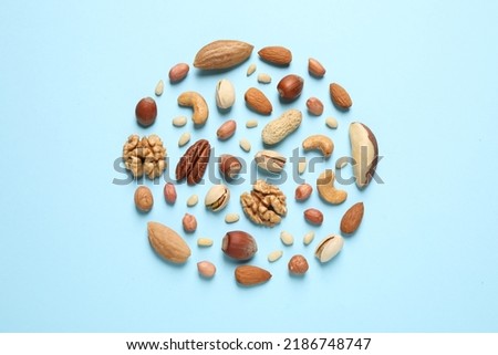 Different delicious nuts on light blue background, flat lay Royalty-Free Stock Photo #2186748747