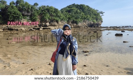 An Asian girl wearing hijab enjoying holiday on a beach while taking picture without showing her face