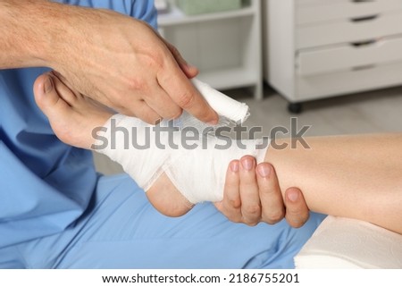 Doctor applying bandage onto patient's foot in hospital, closeup Royalty-Free Stock Photo #2186755201