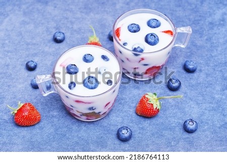 Yogurt desserts with fresh berries on a blue background. Organic breakfast concept.