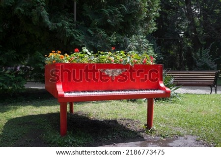 Garden and park decor concept .  Old red piano converted into a flowerbed with different flowers  