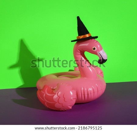 Halloween inflatable flamingo in witch hat on green purple background